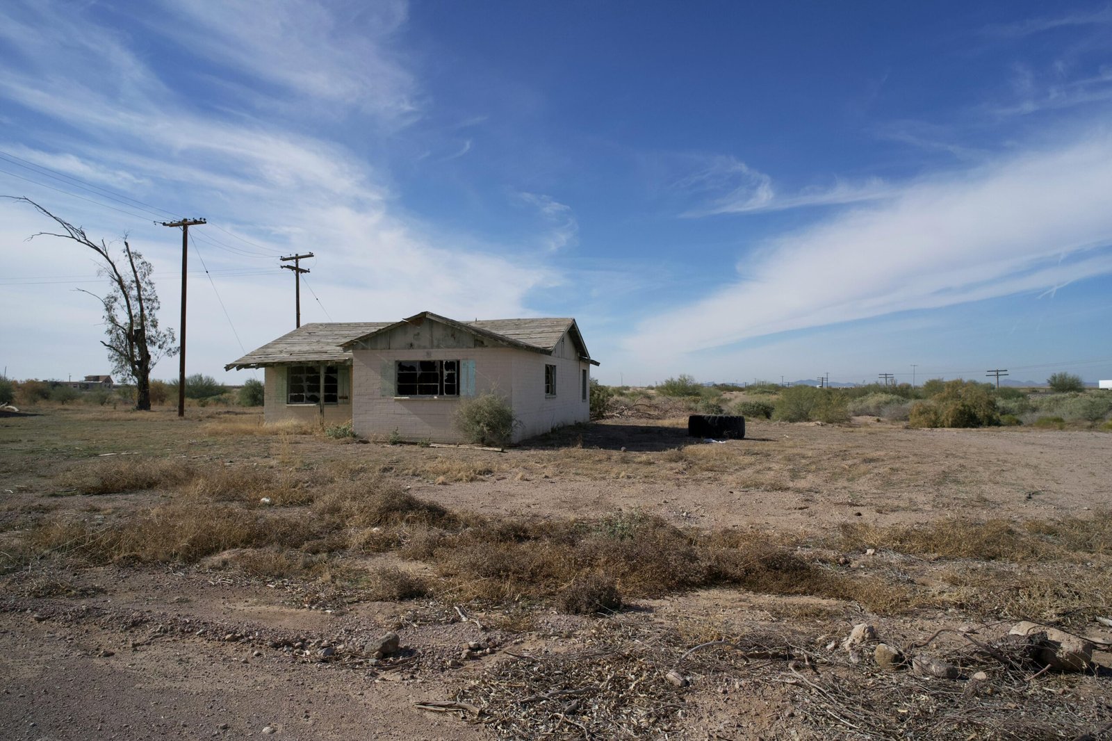 An old abandoned house in the Arizona desert with a clear blue sky background.